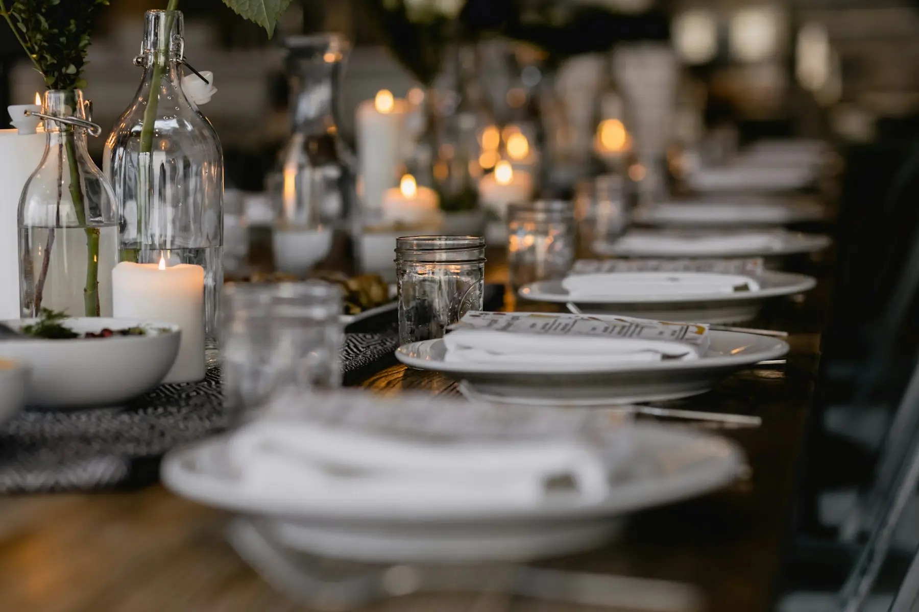 Longue table dressée d'assiettes blanches et de chandelles allumées